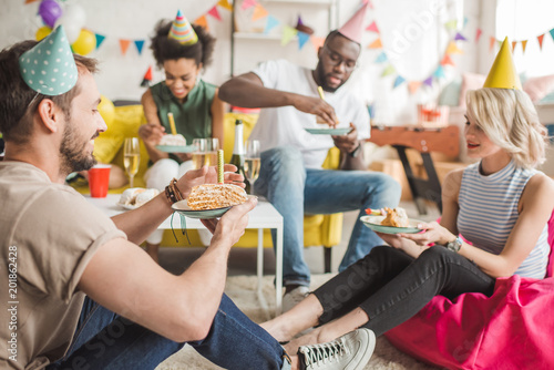 Multiracial smiling friends having party with birthday cake photo