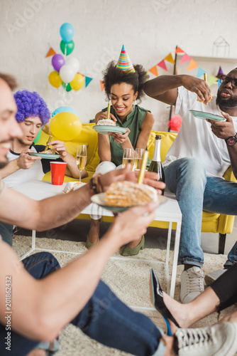 Canvas Print Partying diverse people eating birthday cake and holding drinks
