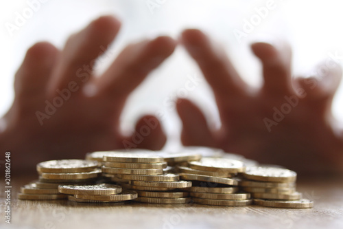 Love of money - Greedy hand grabbing or reaching out for pile of golden coins. Close up - Concept for tax, fraud and greed photo