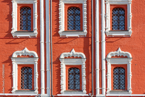 Windows with decorative metal grilles on the facade of red brick of ancient house closeup