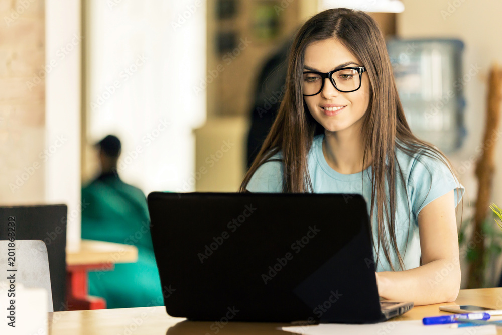 Beautiful dark hair girl student working on the laptop in modern stylish coworking office, successful business concept Beautiful dark hair girl student working on the laptop in modern stylish coworking office, successful business concept
