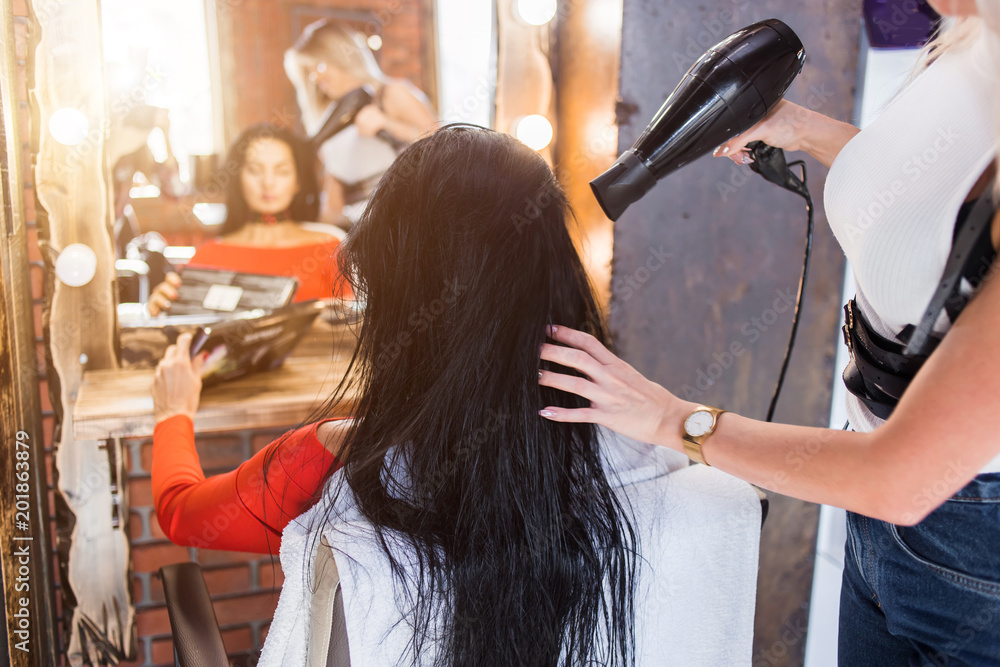 Professional hairdresser with hairdryer dries hair Professional hairdresser with hairdryer dries hair