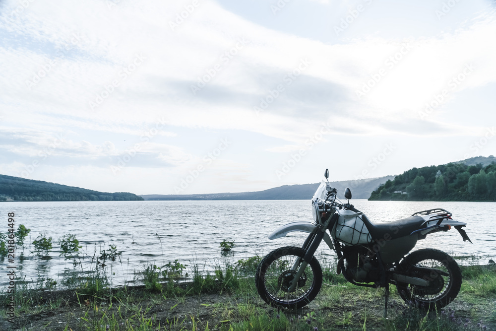 Motorcycle at sunset at lake. off road touring adventure travel enduro active lifestyle Motorcycle at sunset at lake. off road touring adventure travel enduro active lifestyle