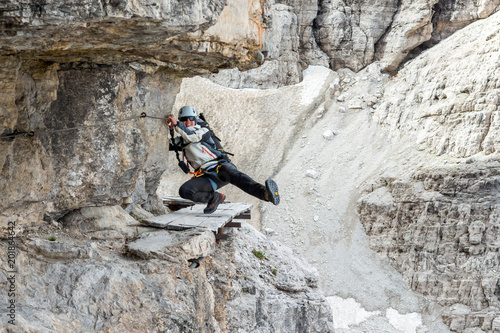 Female climber having some fun on dangerously narrow ledge with via ferrata set.