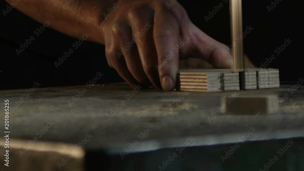 close up on hands of carpenter who cuts a piece of wood with a band saw close up on hands of carpenter who cuts a piece of wood with a band saw