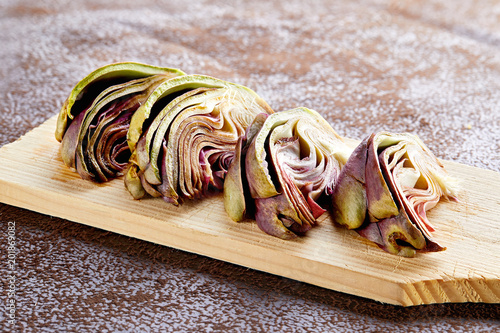 Fresh artichoke quarters on the wooden board