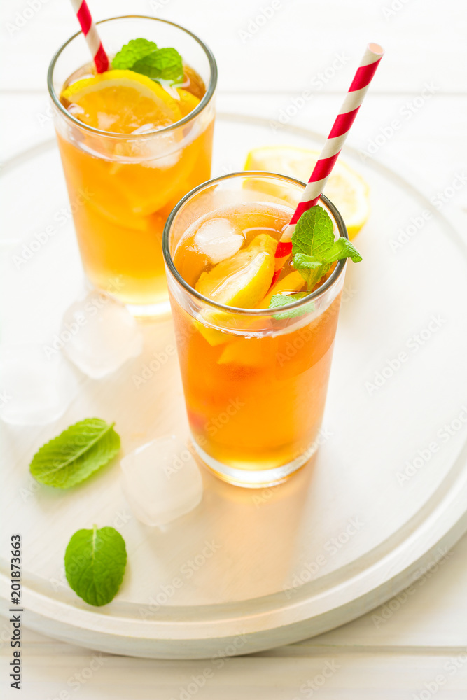 Glasses of iced tea with lemon slices and mint on white wooden background Glasses of iced tea with lemon slices and mint on white wooden background