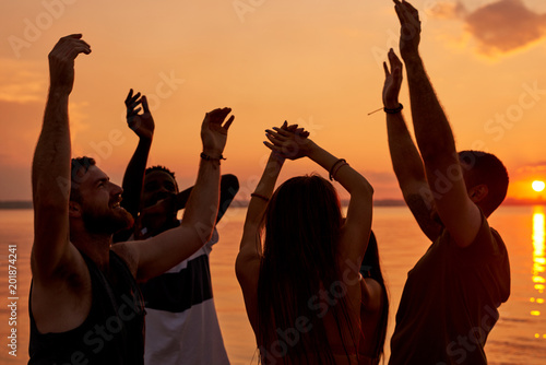 Slika na platnu Cheerful positive young friend dancing in light of sunset enjoying beach party a