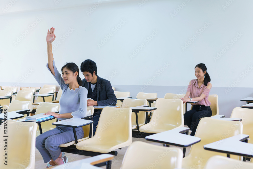 Young woman and friend student raising hands in a classroom showing ready answer. concept of education. Young woman and friend student raising hands in a classroom showing ready answer. concept of education.