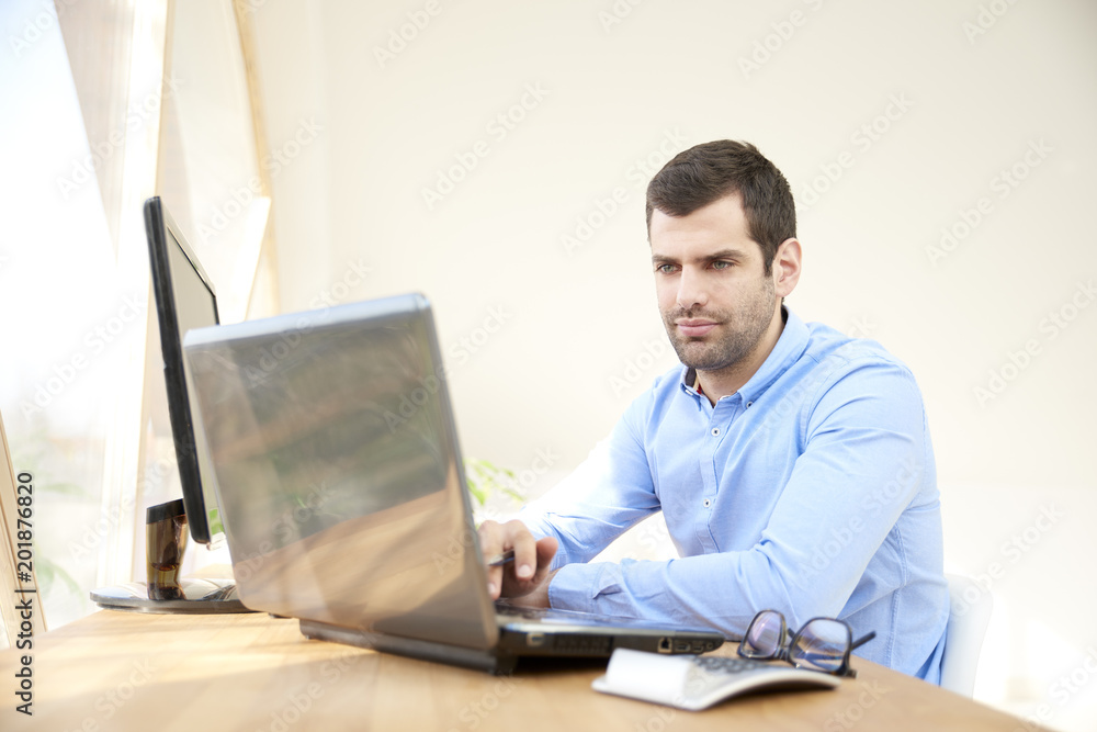 Thinking young businessman working on laptop