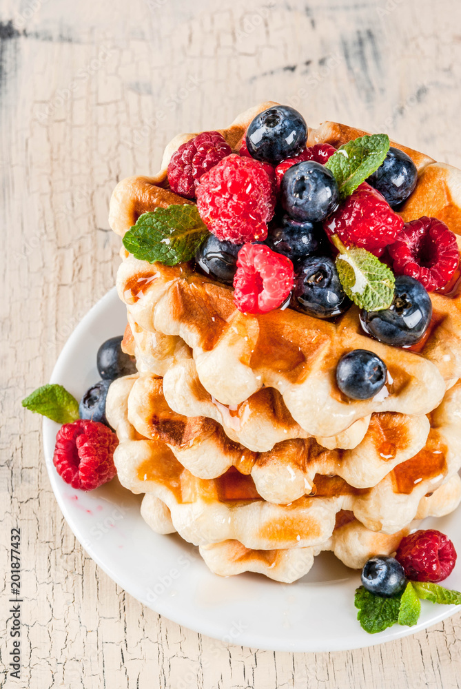 Belgian waffles with raspberries, blueberries and syrup, homemade healthy breakfast, light concrete background copy space Belgian waffles with raspberries, blueberries and syrup, homemade healthy breakfast, light concrete background copy space