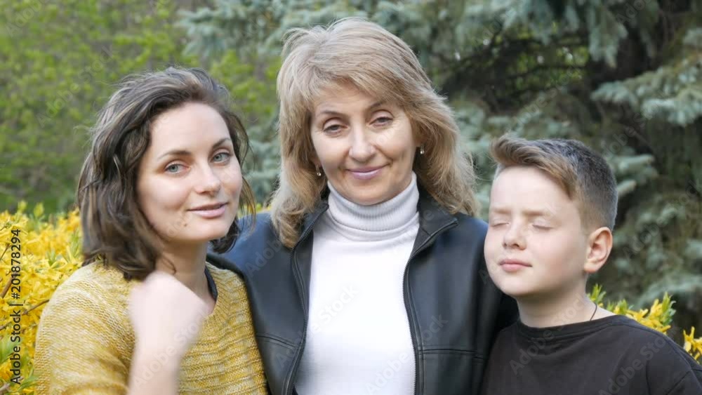 An adult daughter and a teenager meet their senior mother hug her and kiss her. Spring Mother's Day An adult daughter and a teenager meet their senior mother hug her and kiss her. Spring Mother's Day