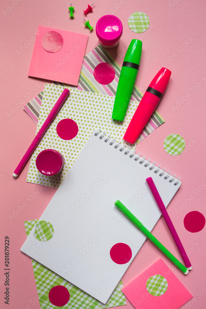 Pink and green markers and notepad for writing on a pink background flat top view with copy space, pattern from stationery accessories for school Pink and green markers and notepad for writing on a pink background flat top view with copy space, pattern from stationery accessories for school