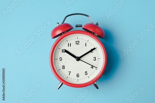 Red vintage alarm clock on light blue color background photo