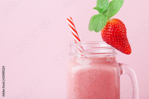 Pink strawberry smoothie or milkshake in mason jar decorated mint on pastel table. Healthy food for breakfast and snack.