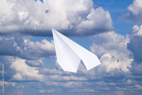 White paper airplane in a blue sky with clouds. The message symbol in the messenger