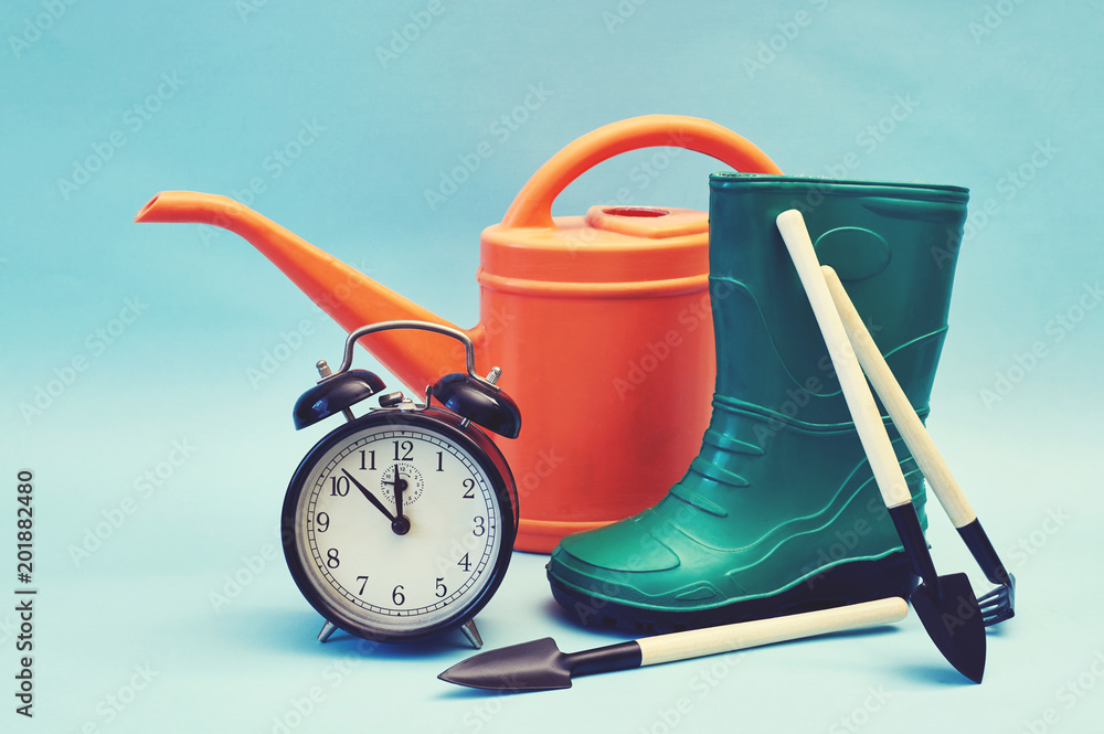 boots with garden tools, alarm clock and watering can