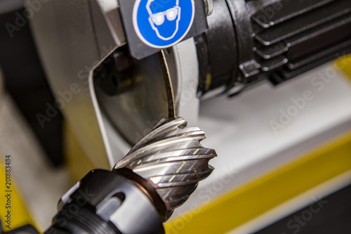 The machine operator regrinding the drill tool for sharpen the drill tool with grinding wheel.