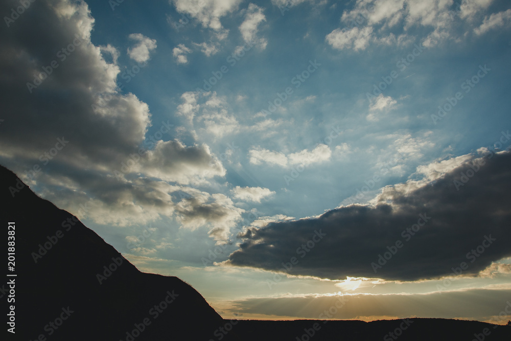 Obraz premium Amazing evening sky clouds and sun lights. Landscape of sunset in the mountains. Beautiful sunrise on the nature.