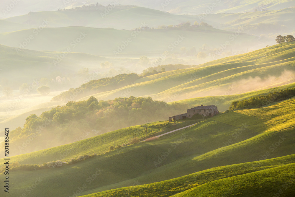 Italian Farmhouse in the valley with fog at sunrise