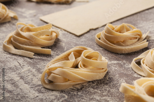 Raw tagliatelle nest and dough on kitchen table