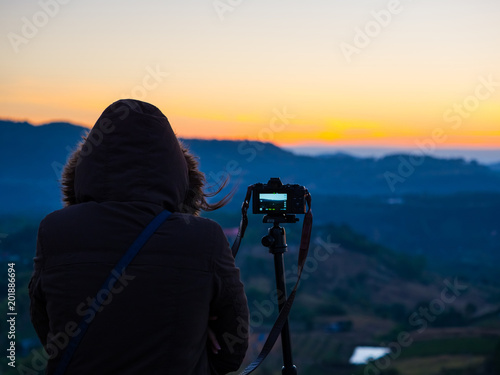 travel and photographer concept from backside of woman with hoodie cloth stand and see mountain view with take picture by her camera