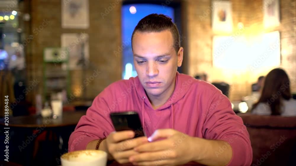 Attractive hispanic man (a businessman, a student or a startup) with an attractive smile using mobile phone. Young boy texting on smartphone. 4 k Technologies concept. Attractive hispanic man (a businessman, a student or a startup) with an attractive smile using mobile phone. Young boy texting on smartphone. 4 k Technologies concept.