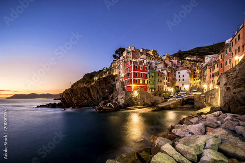 Riomaggiore fisherman village at sunset. Riomaggiore is one of five famous colorful villages of Cinque Terre in Italy, suspended between sea and land on sheer cliffs. Liguria, Italy