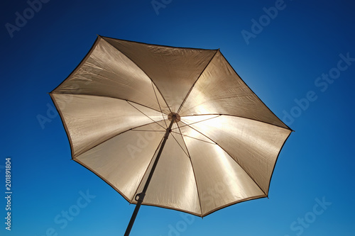 The beach umbrella protects from the bright sun  bottom view. Yellow sun protector under blue sky - summer vacation background