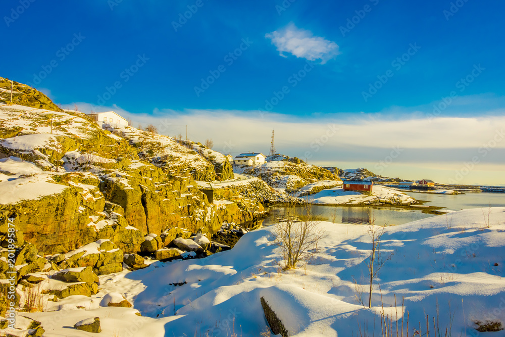 Outdoor view with some buildings in the bay in Lofoten Islands surrounded with snowy mountains and colorful winter station