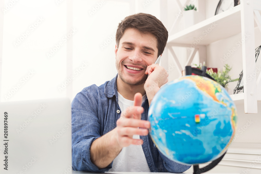Young man playing with globe and taking on phone Young man playing with globe and taking on phone