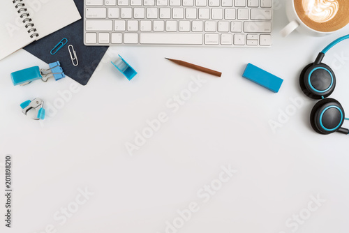 Flat lay, top view office table desk. Workspace with blank note book, keyboard, Blue office supplies and coffee cup on white background.