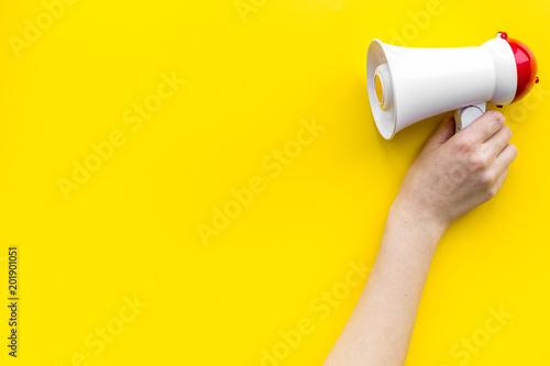 Attract attention concept. Megaphone in hand on yellow background top view copy space