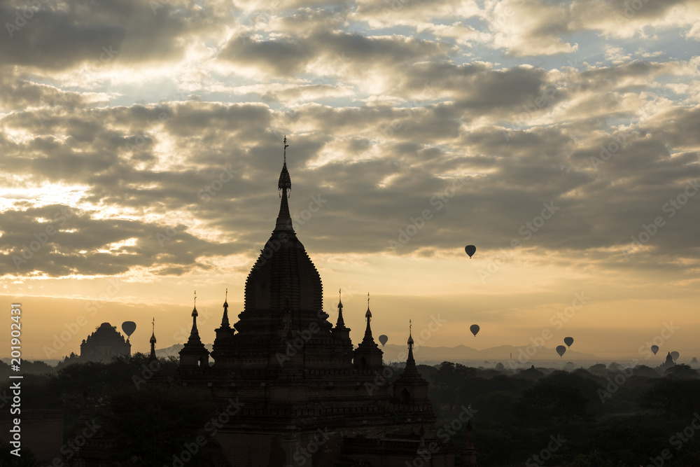 Silhouette of a Temple in Bagan with many hot air balloons during sunrise in Myanmar