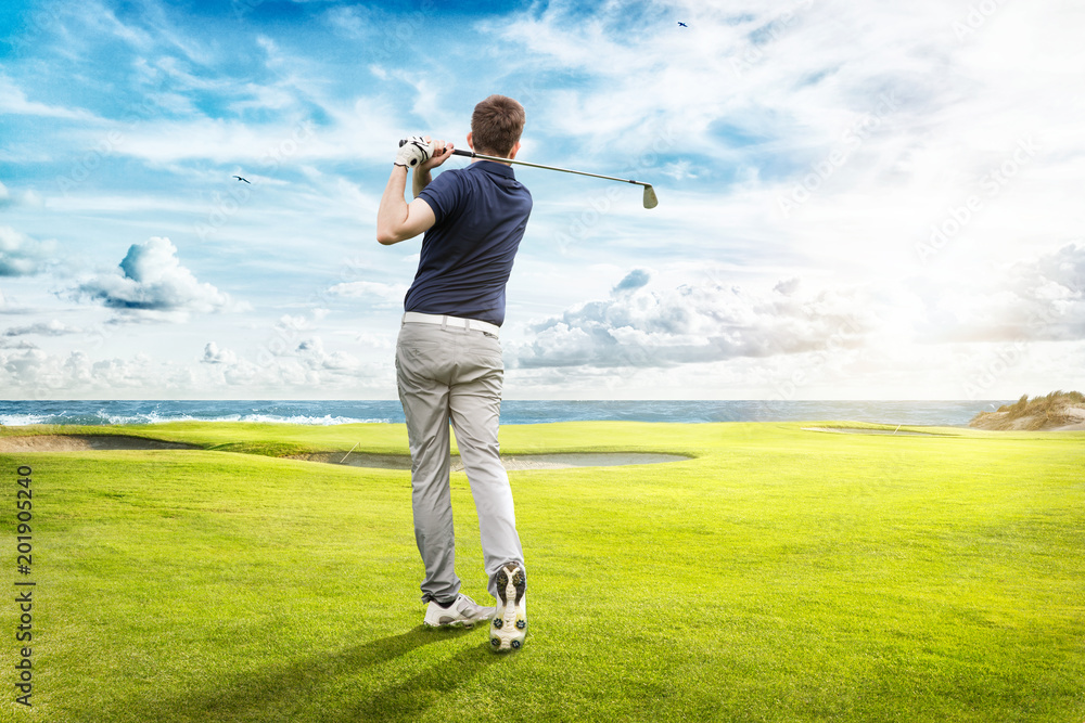 Junger Golfspieler spielt auf Golfplatz am Meer Junger Golfspieler spielt auf Golfplatz am Meer