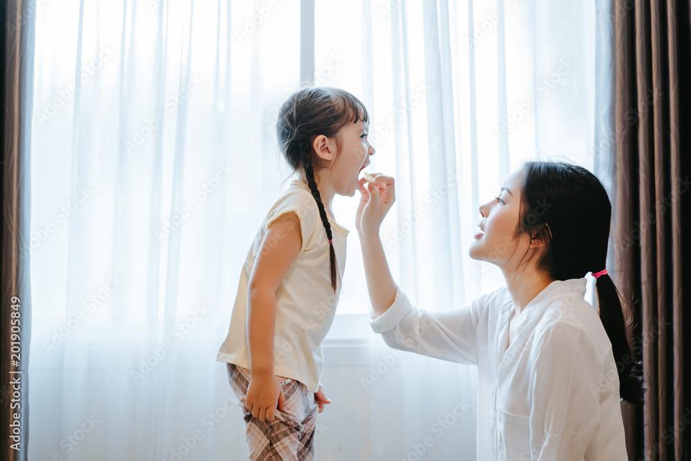 Mother feeding snack to daughter eating in the morning at home side window funny family together lifestyle. Mother feeding snack to daughter eating in the morning at home side window funny family together lifestyle.