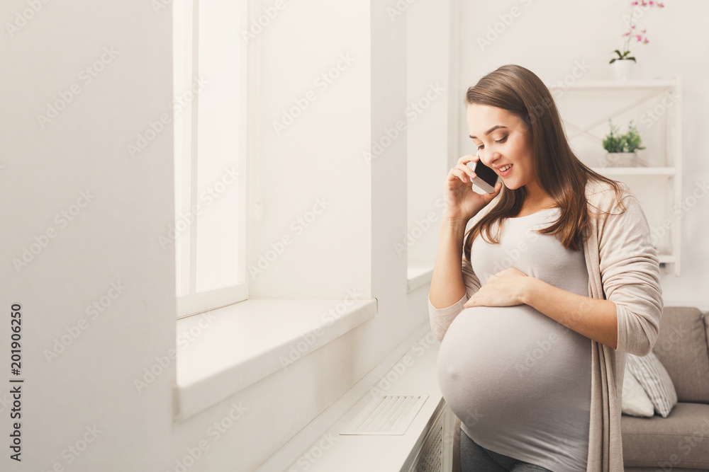 Smiling pregnant woman talking on her smartphone Smiling pregnant woman talking on her smartphone