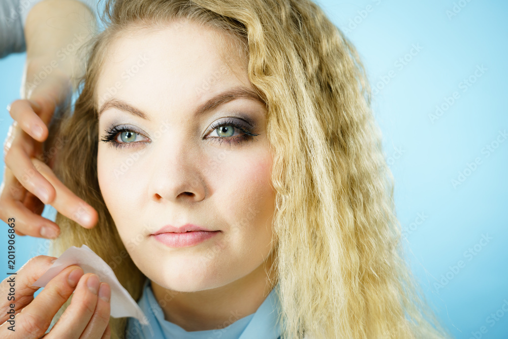 Woman using oil blotting tissues on model Woman using oil blotting tissues on model