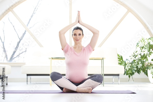 Full length shot of pregnant young woman performing a yoga routine to relax at home.