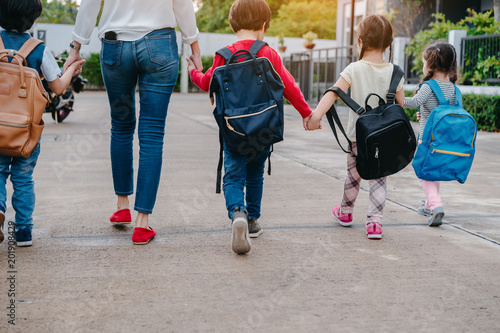 Back to School of Mother and pupil and kids holding hands going to school