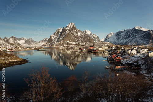 Fototapeta Naklejka Na Ścianę i Meble -  View of beautiful Sacrisoya village in winter time with montains in background with light of sunrise. Lofoten, Norway.