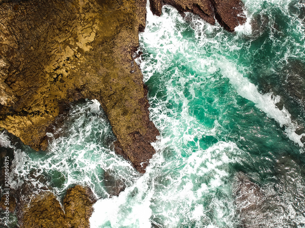 Aerial shot of ocean waves crashing coastline