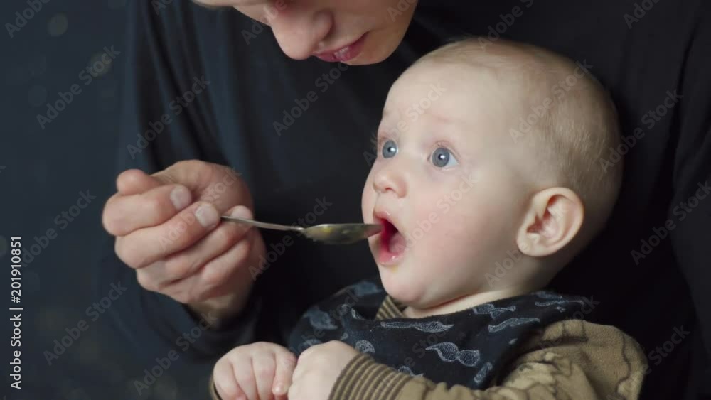 Father feeds the baby. Funny baby eats with spoons. Care for the child. 4k Father feeds the baby. Funny baby eats with spoons. Care for the child. 4k