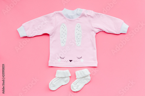 Newborn baby's background. Clothes for small girl with booties on pink background top view