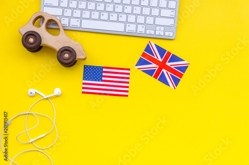 Teach english for a child. Funny english. British and american flags  computer keyboard  toy on yellow background top view copy space