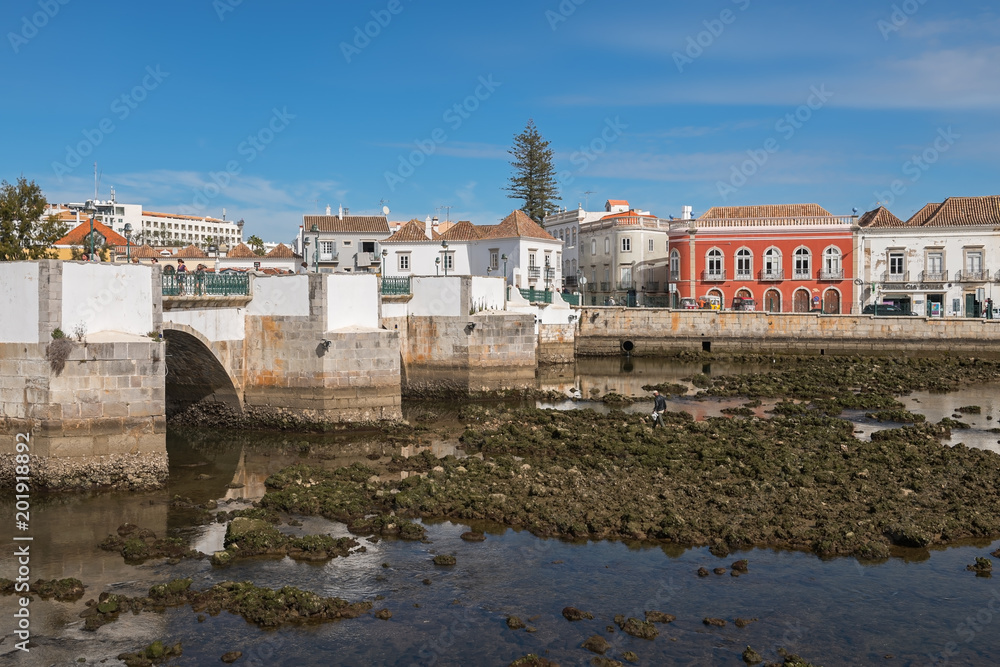 Obraz premium View of the old Roman bridge and Gilao river in the city of Tavira at low tide, Portugal