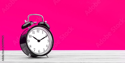 alarm clock on a wooden table on a colored background