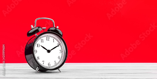 alarm clock on a wooden table on a colored background