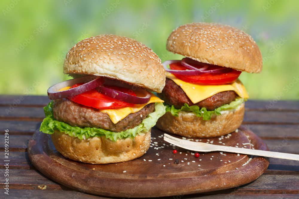 Two delicious burgers on wooden board. Fresh, tasty hamburgers. Soul food. Two delicious burgers on wooden board. Fresh, tasty hamburgers. Soul food.
