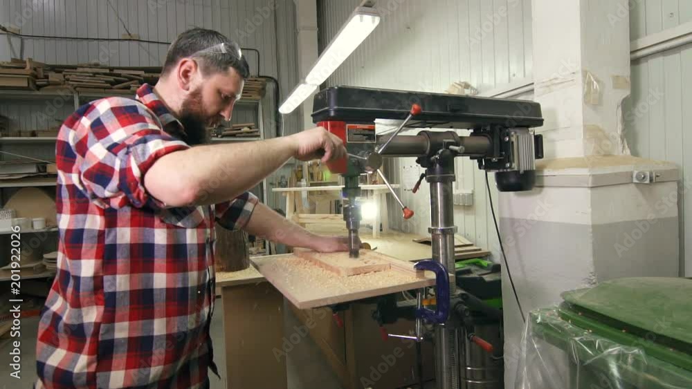 man carpenter in a shirt using drilling machine in slowmotion man carpenter in a shirt using drilling machine in slowmotion